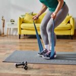 Cropped view of woman doing a resistance band workout on a home mat.