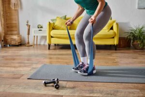Cropped view of woman doing a resistance band workout on a home mat.