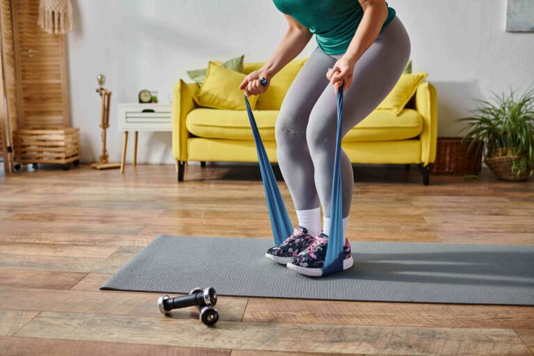 Cropped view of woman doing a resistance band workout on a home mat.