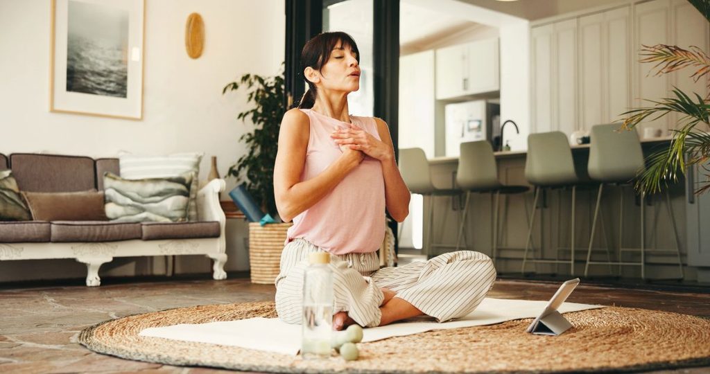 Woman placing hands on her chest in a moment of calm, representing neurowellness and nervous system safety.