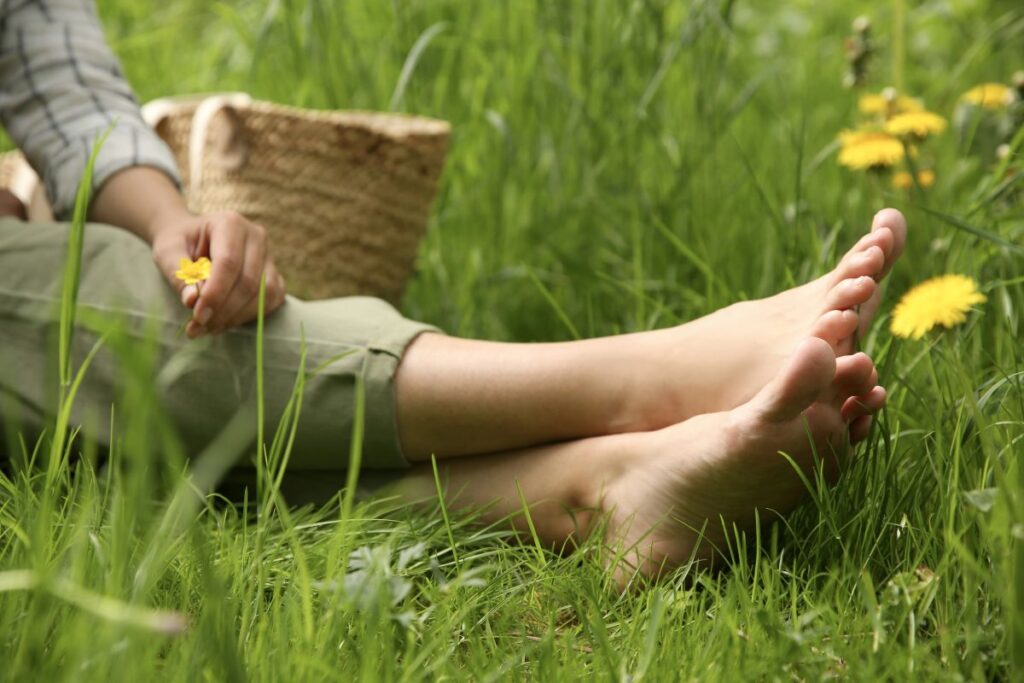 Grounding outdoors barefoot in grass with wildflower, natural stress relief and calm lifestyle
