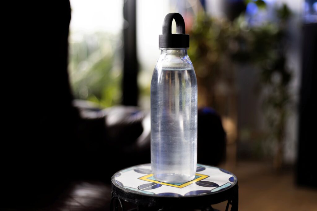 Clear water bottle on a patterned table in a softly lit indoor space.