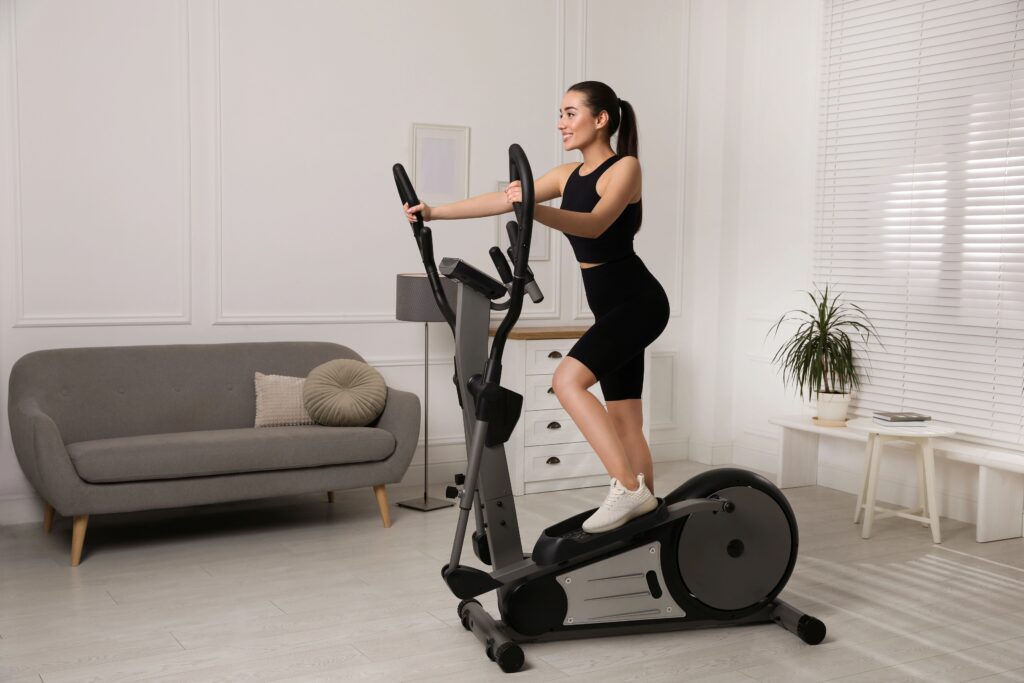 “Person exercising on an elliptical machine in a bright, cozy living room with natural light.
