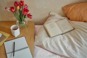 Cozy bedside scene with tea, tulips, an open book, and soft morning light
