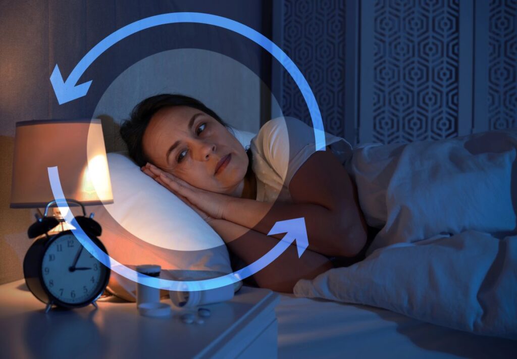Person lying awake in bed at night with clock and pills nearby