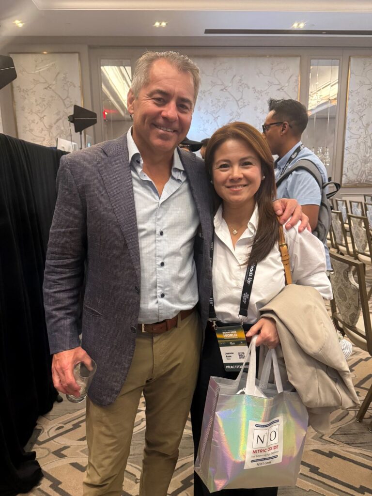 Dr. Nathan Bryan, and Joanne Reyes standing together at the Biohackers World Conference in New York, wearing event badges in a warm, professional setting.