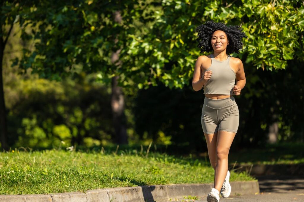 A woman jogging outdoors in soft morning light, showing active movement and vitality—an example of how women who age well prioritize daily habits that support strength and longevity.